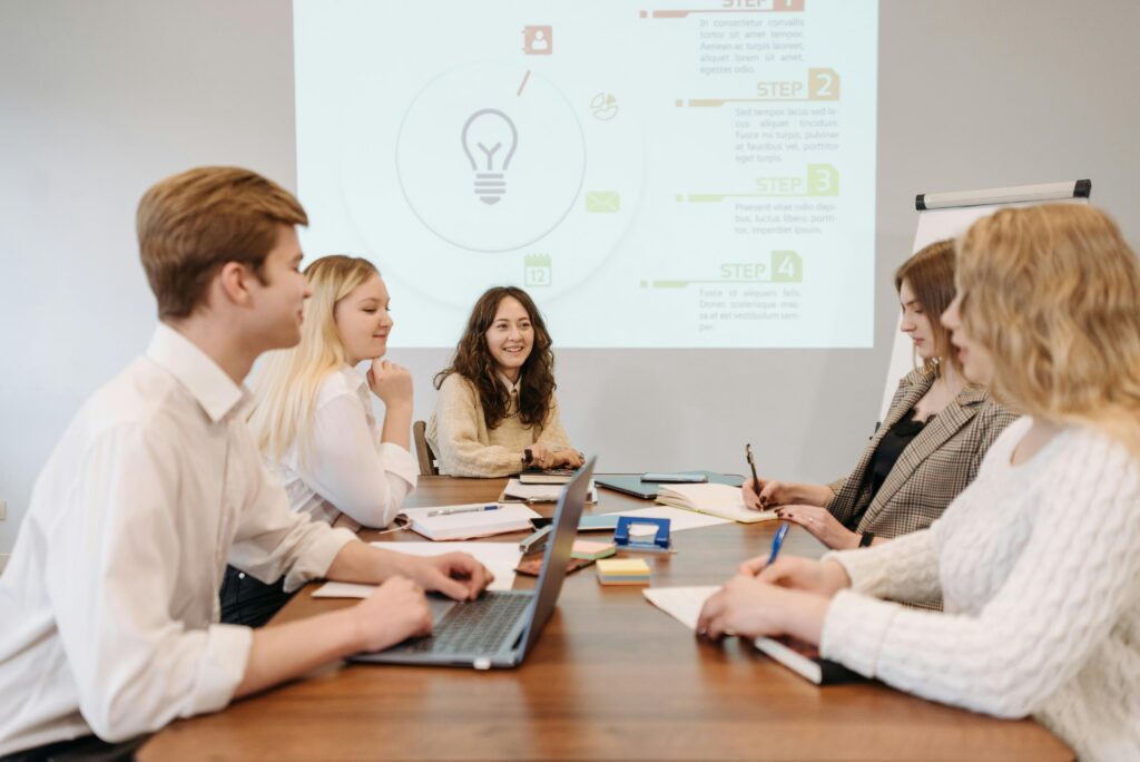 A group of sales and marketing professionals collaborating around a table while reviewing campaign plans and discussing strategy.