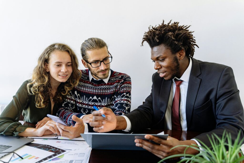 A professional sales representative confidently presenting a service to clients in a business meeting environment.